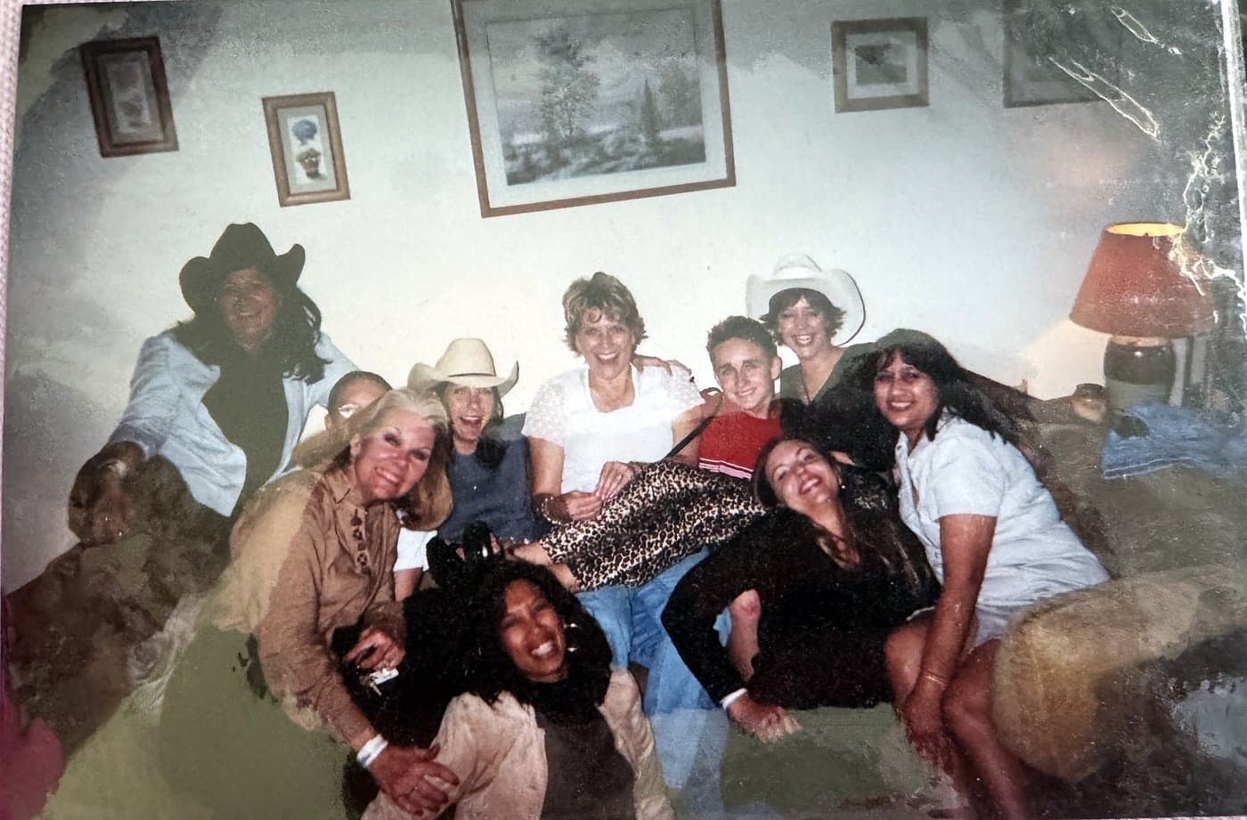 A crowded couch full of Eve Hess's friends laughing, some in cowboy hats, at apartment 1130