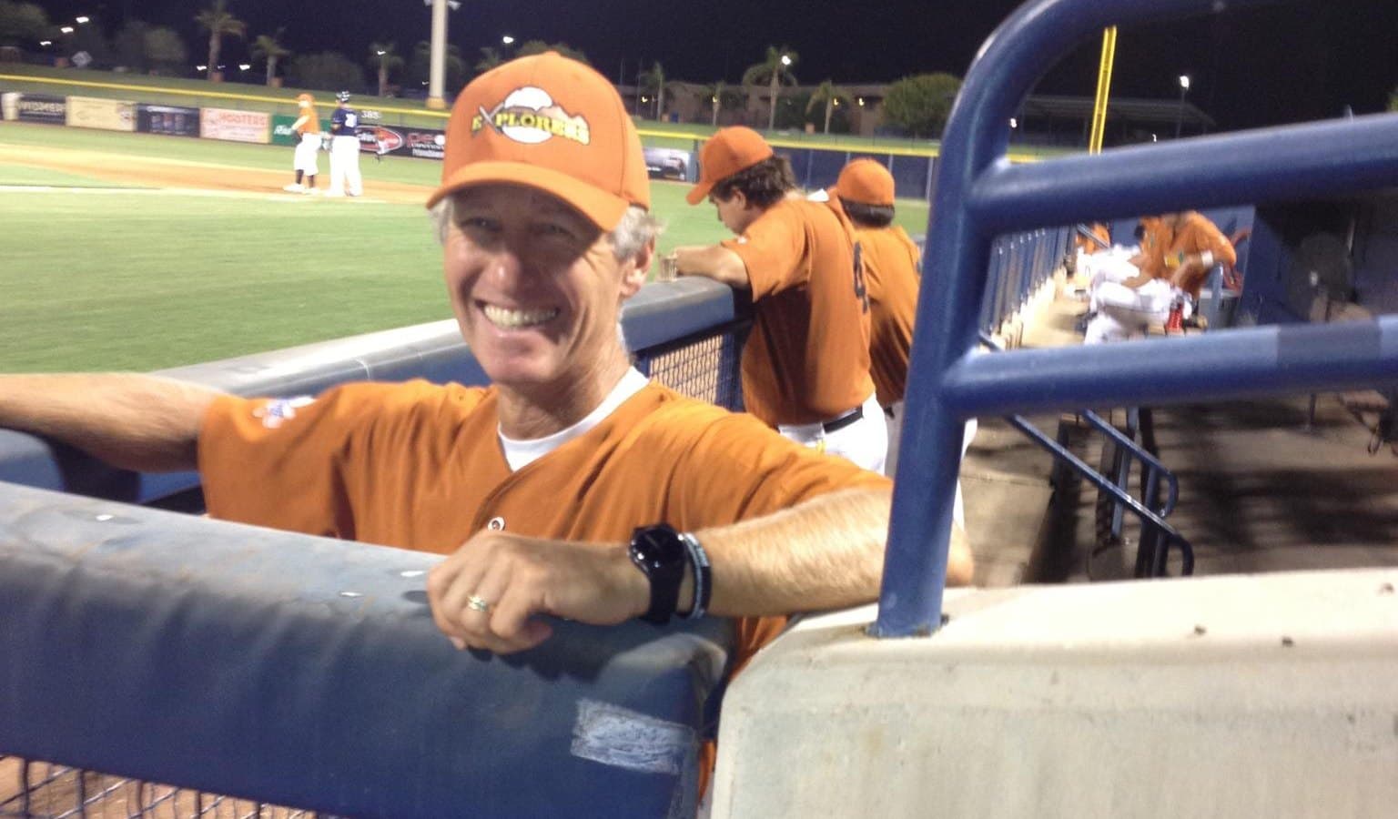 Dr. Robert Larson in his Peoria Explorers uniform, leaning on the dugout rail the night of his professional pitching debut at fifty, September 2012
