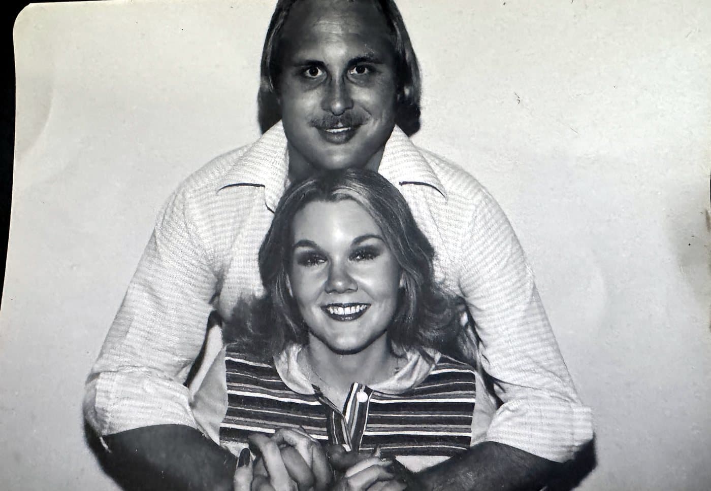 Black-and-white photo of a young Eve Hess smiling, with Rod Hess behind her holding her hands