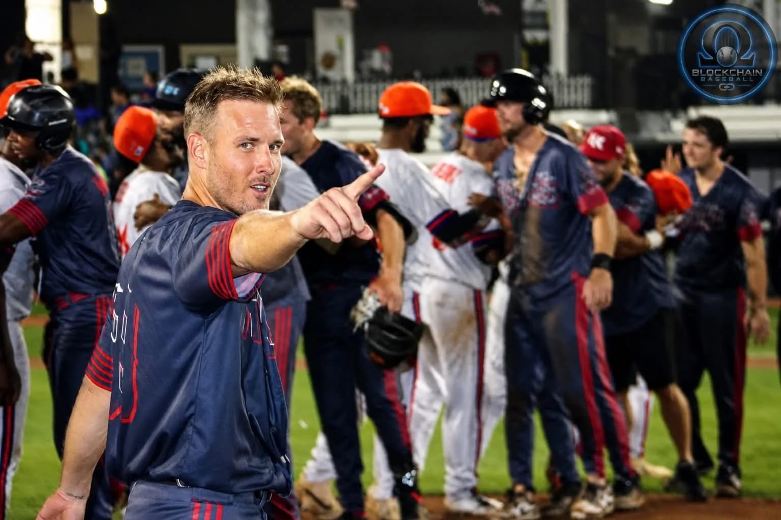 Isaac Hess pointing at the camera after an OBA championship win, teammates celebrating behind him