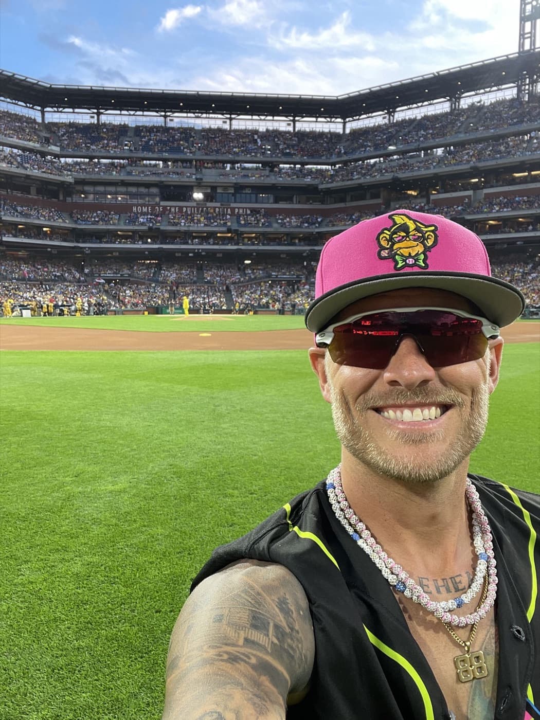 Isaac Hess smiling in a Party Animals cap on the field at Citizens Bank Park, with the stands full behind him